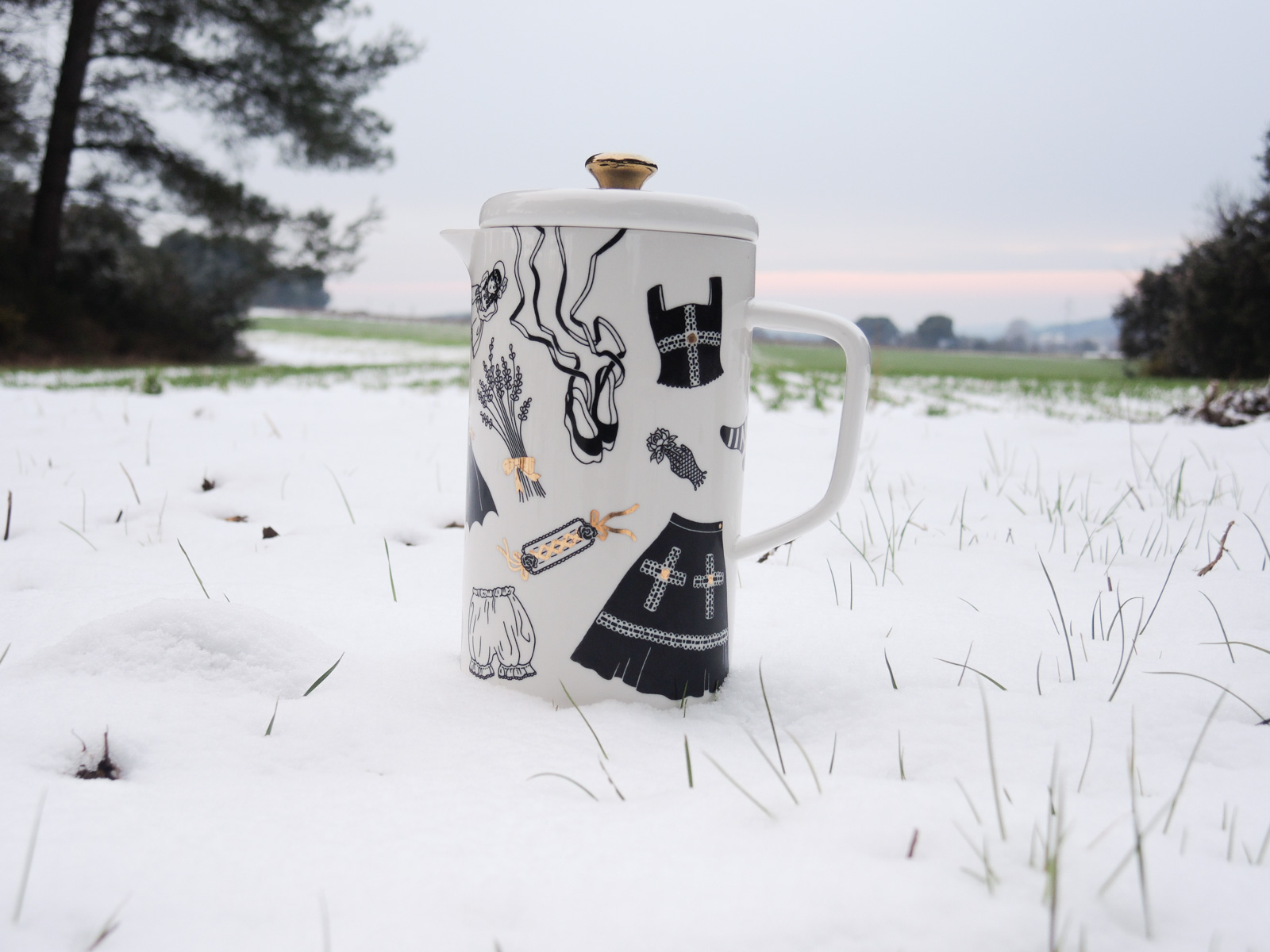 Black coffee pot - 3rd one - from “Oldschool Lolita”, a collection of painted porcelains by messalyn, standing in the snow in a field at sunset