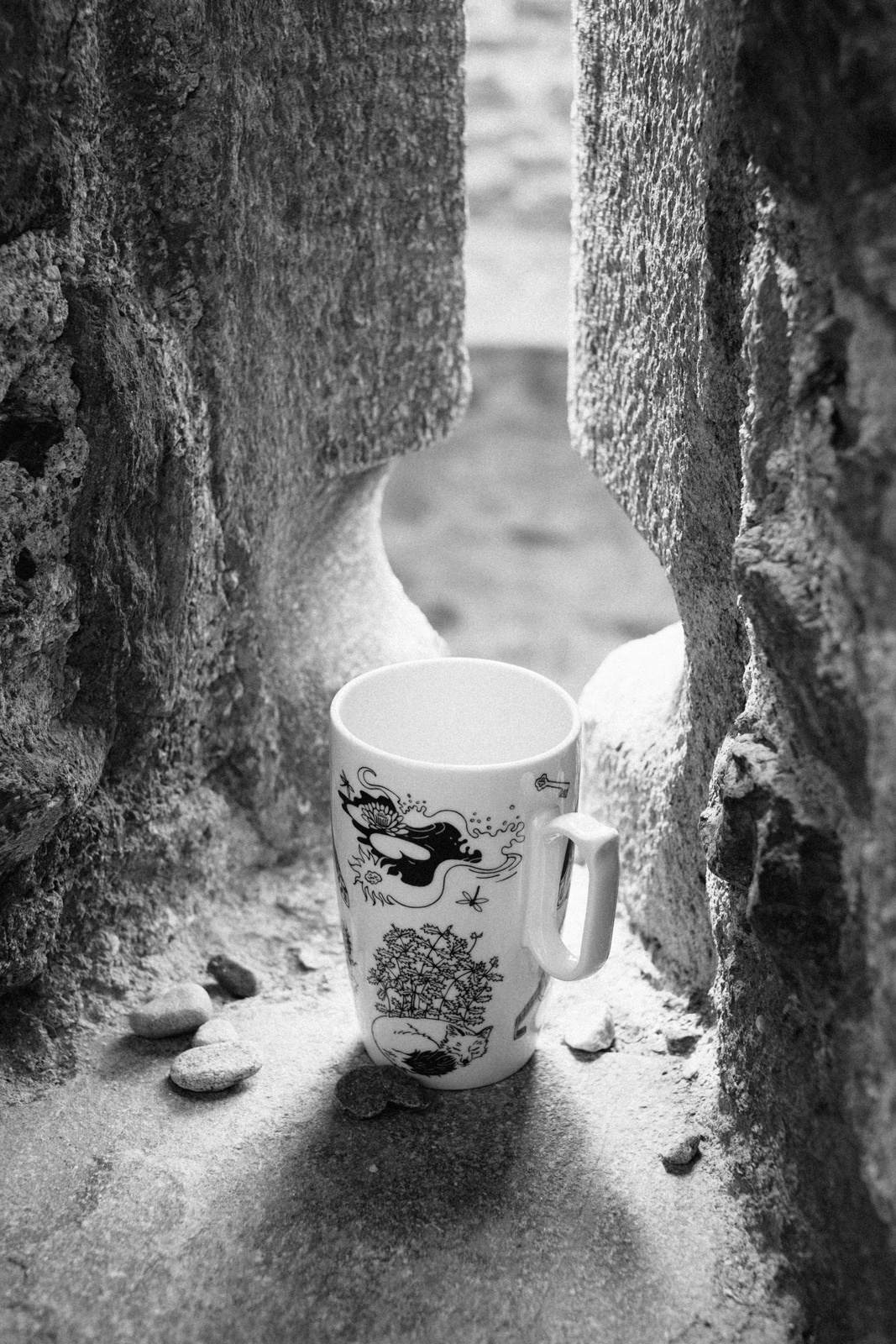 Black and white photograph of a purple mug from “Enchanteresse”, a collection of painted porcelains by messalyn, standing on a windowsill in the italian castle of Fénis